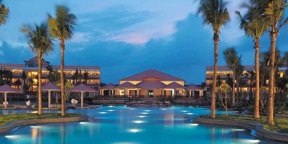 A Breath Taking Picture Postcard View In Pondicherry’s Nature-friendly Resort With Tall Trees And Beautiful Lighting On The Poolside.